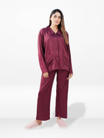 Woman wearing a burgundy satin pajama set on a white background