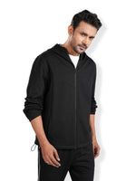 Man wearing a black hoodie and pants on a white background