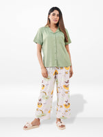 Woman wearing a green shirt and patterned pants on a white background
