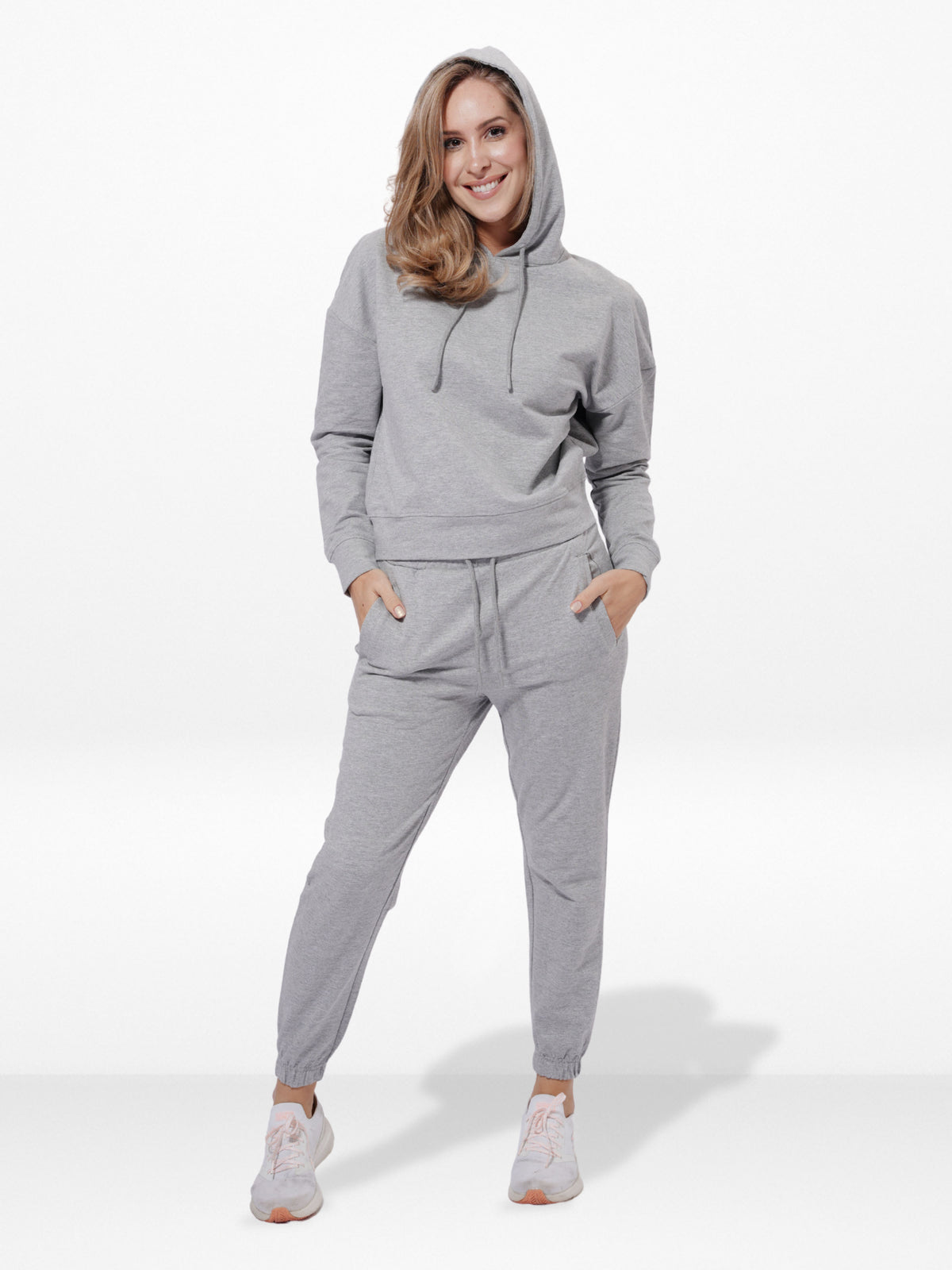 Woman wearing a gray hoodie and jogger set on a white background