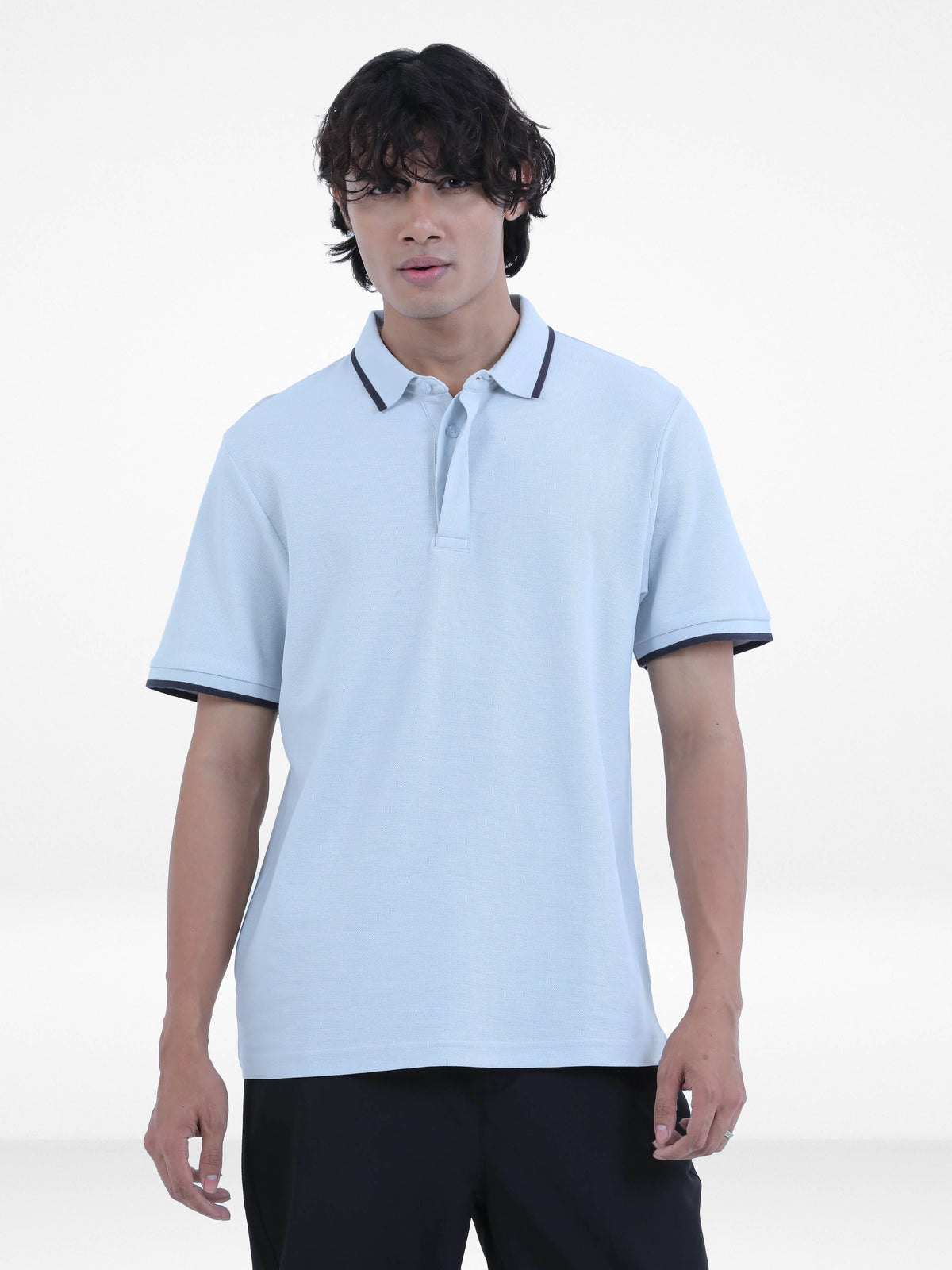 Person wearing a light blue polo shirt with black trim on a white background