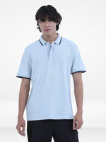 Person wearing a light blue polo shirt with black trim on a white background