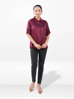 Woman wearing a burgundy shirt and black pants on a white background