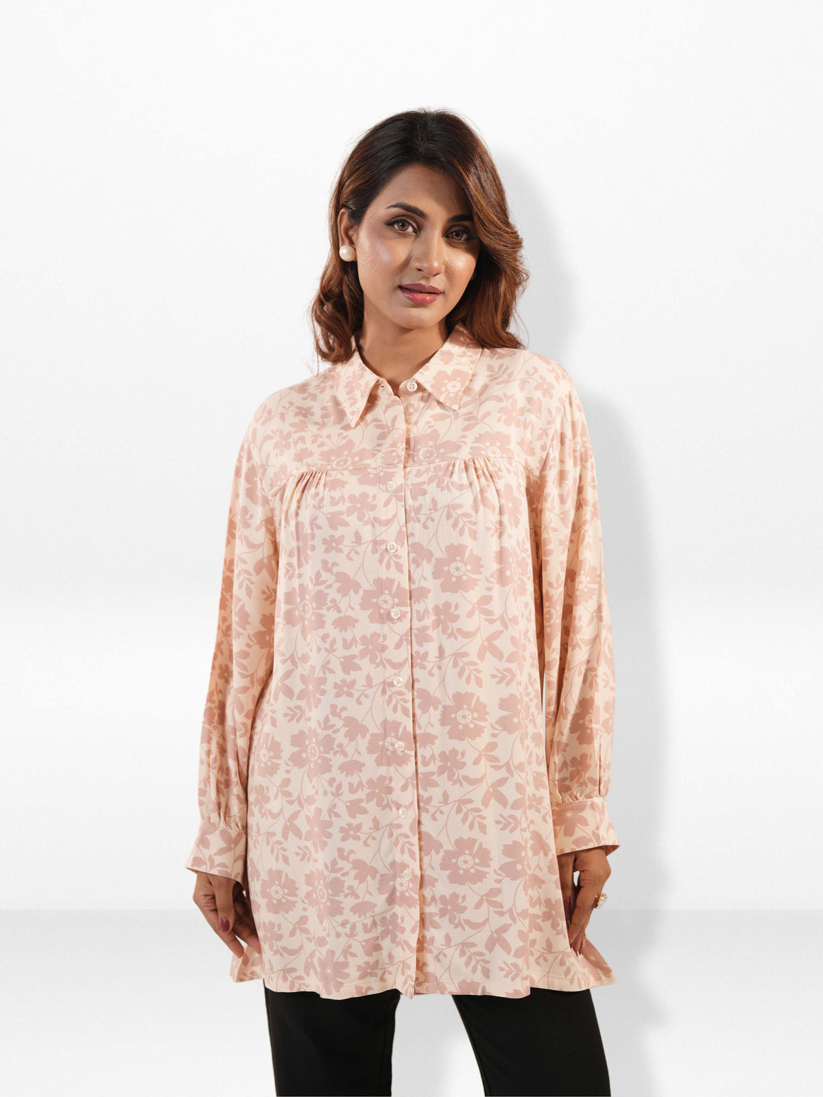 Woman wearing a light pink floral blouse against a white background